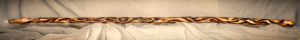 A six-foot long, three-inch diameter oak staff, burned with artistic representations of flames. The left side of the image is the top of the staff showing a clear quartz crystal embedded in the top. 3 inches down from the top, copper wire is braided around the staff.